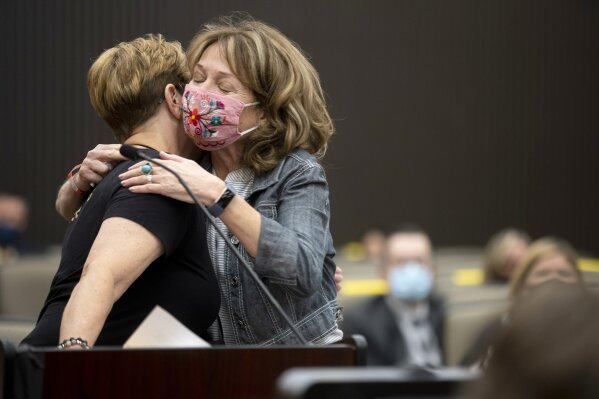 Debbi McMullan, left, is embraced by Melanie Barbeau as they confront Joseph James DeAngelo at the Sacramento County Courthouse during the third day of victim impact statements on Thursday, Aug. 20, 2020, in Sacramento, Calif. DeAngelo, a former California police officer, has admitted to being the infamous Golden State Killer, committing 13 murders and nearly 50 rapes between 1975 and 1986. DeAngelo killed McMullan's mother, Cheri Domingo, and Domingo's boyfriend, Gregory Sanchez. (Santiago Mejia/San Francisco Chronicle via AP, Pool)