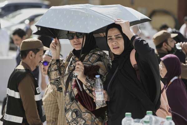 Egyptian pilgrims share an umbrella outside the Grand Mosque during the annual hajj pilgrimage at the holy city of Mecca, Saudi Arabia, Tuesday, June 3, 2025. (AP Photo/Amr Nabil)
