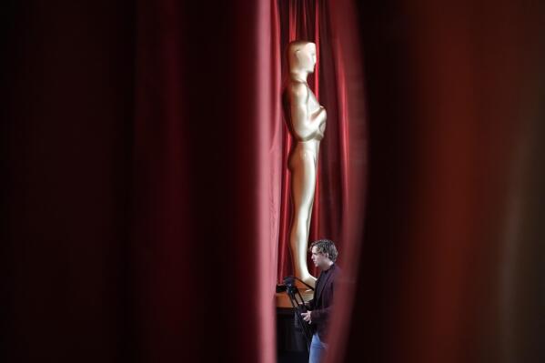 A person walks by an Oscar statue during preparations for Sunday's 95th Academy Awards, Saturday, March 11, 2023, in Los Angeles. (AP Photo/John Locher)