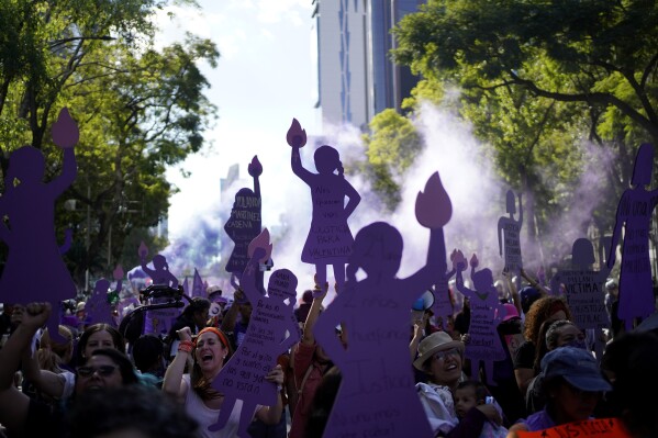 FILE - Women, many holding up purple silhouette cutouts that depict the anti-monument "Mujeres que luchan" or women who fight, march to the Zocalo to mark International Day for the Elimination of Violence against Women, in Mexico City, Nov. 25, 2023. President Andres López Obrador and leading presidential candidate Claudia Sheinbaum have claimed that the number of homicides dropped during the current administration. But Catholic leaders, during nationwide forums that the church held in 2023, have echoed the fears spread among thousands of average citizens who shared how violence broke their lives. (AP Photo/Aurea Del Rosario, File)