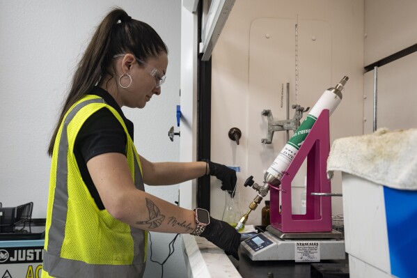 An operator tests the contents of a used refrigerant cylinder in a lab at the A-Gas Rhome facility on Monday, Oct. 9, 2023, in Rhome, Texas. The company takes in shipments of refrigerators and tanks from around the country and beyond, drains them, then purifies and reclaims the chemicals, shipping out recycled product. This prevents the need for new chemical production. (AP Photo/Sam Hodde)