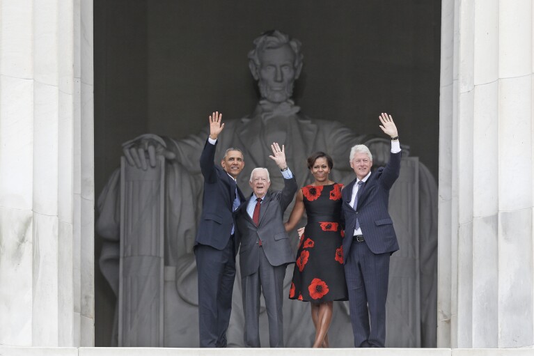 FILE - President Barack Obama and first lady Michelle Obama, former President Jimmy Carter and former President Bill Clinton wave as they leave 50th Anniversary of the March on Washington where Martin Luther King Jr., spoke in front of the Lincoln Memorial in Washington, Wednesday, Aug. 28, 2013. (AP Photo/Charles Dharapak, File)