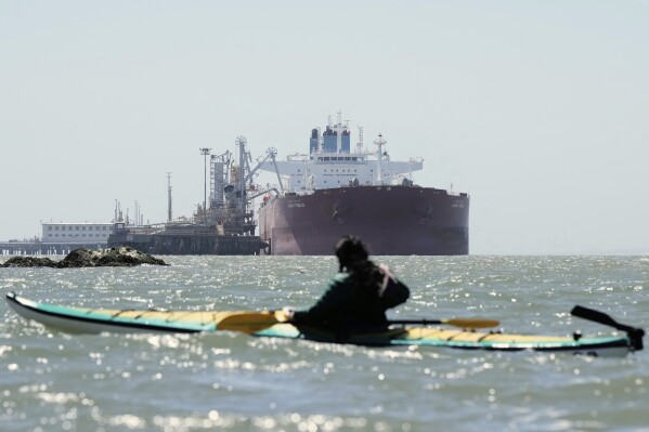 Juan Bay, president of the Waorani people of Ecuador, foreground, looks at an oil tanker docked at the Chevron Long Wharf, Thursday, June 19, 2025, in Richmond, Calif. (AP Photo/Godofredo A. Vásquez)