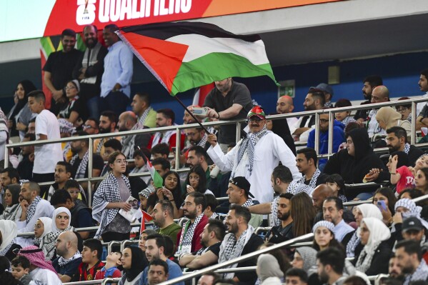 A Palestinian fan waves Palestine national flag during a qualifying soccer match against Australia of the FIFA World Cup 2026 at Jaber Al -Ahmad stadium in Kuwait, Tuesday, Nov. 21, 2023. (AP Photo/Jaber Abdulkhaleg)