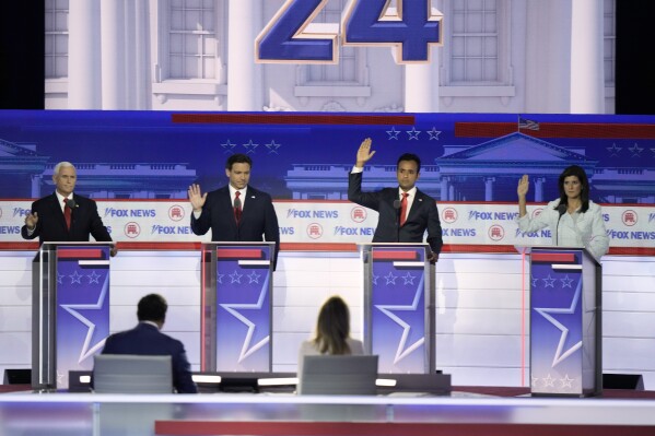 Former Vice President Mike Pence, Florida Gov. Ron DeSantis, businessman Vivek Ramaswamy and former U.N. Ambassador Nikki Haley raise their hands in response to a question if they would support the eventual party nominee during a Republican presidential primary debate hosted by FOX News Channel Wednesday, Aug. 23, 2023, in Milwaukee. (AP Photo/Morry Gash)