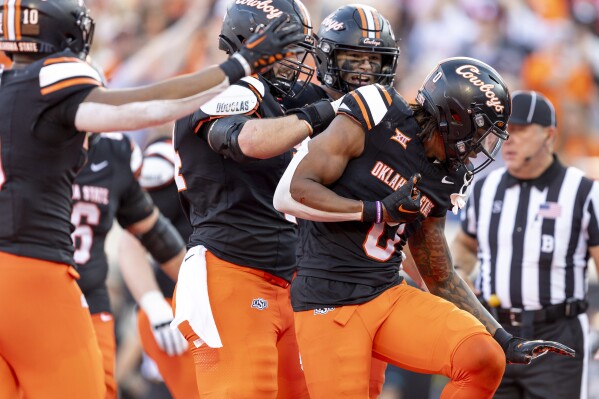 Oklahoma State running back Ollie Gordon II, right, celebrates with Oklahoma State tight end Josiah Johnson, center, and offensive lineman Preston Wilson, right, after scoring a touchdown in the second half of an NCAA college football game Saturday, Nov. 4, 2023, in Stillwater, Okla. (AP Photo/Mitch Alcala)