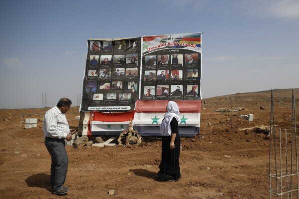 
              In this Thursday, Oct. 4, 2018 photo, a Druze family visits a memorial erected in honor of the 37 Druze who killed during a stunning Islamic State attack at the village of Shreihi in the southern province of Sweida, Syria. Three months after a stunning Islamic State attack on a southeastern corner of Syria in which more than 200 people were killed and 30 women and children abducted, tensions are boiling over, and young men are taking up arms. It is a stark change for a province that managed to stay on the sidelines of the seven-year Syrian war and where most villagers worked grazing livestock over surrounding hills. (AP Photo/Hassan Ammar)
            