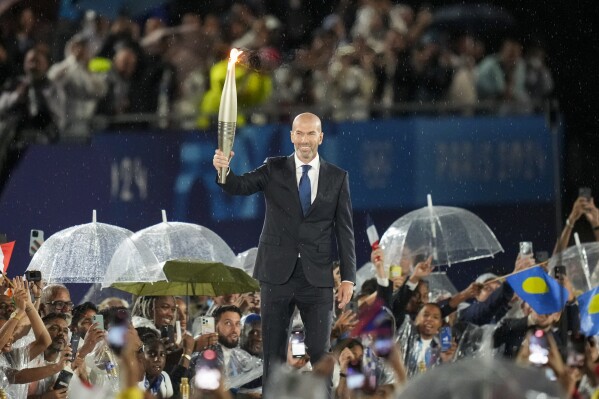 Zinedine Zidane carries the Olympic torch in Paris, France, during the opening ceremony of the 2024 Summer Olympics, Friday, July 26, 2024. (ĢӰԺ Photo/Thibault Camus)