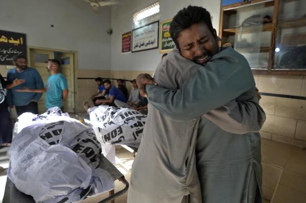 People mourn next to the bodies of fire fighters who died in a fire, at a morgue in Karachi, Pakistan, Thursday, April 13, 2023. A massive fire broke out in a garment factory in the southern Pakistan port city of Karachi. The cause of the blaze, which ripped through the factory Wednesday night and eventually caused it to collapse, was not immediately known, rescue officials and police said. (AP Photo/Fareed Khan)