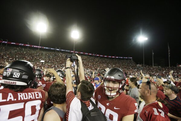 Washington State fans and players celebrate on the field after team's win over Wisconsin in an NCAA college football game, Saturday, Sept. 9, 2023, in Pullman, Wash. (AP Photo/Young Kwak)