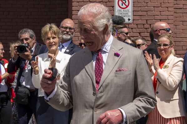 King Charles looks at the puck after participating in a ceremonial puck drop during a visit to Lansdowne Park in Ottawa, Canada, on Monday, May 26, 2025. (Christinne Muschi/The Canadian Press via AP)