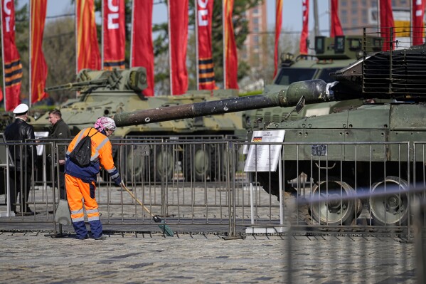 A municipal worker cleans an area near a Leopard 2A6 tank that belonged to the Ukrainian army on display in Moscow, Tuesday, April 30, 2024. The Russian military put some of the equipment captured from Ukrainian forces on display in Moscow. (AP Photo/Alexander Zemlianichenko)