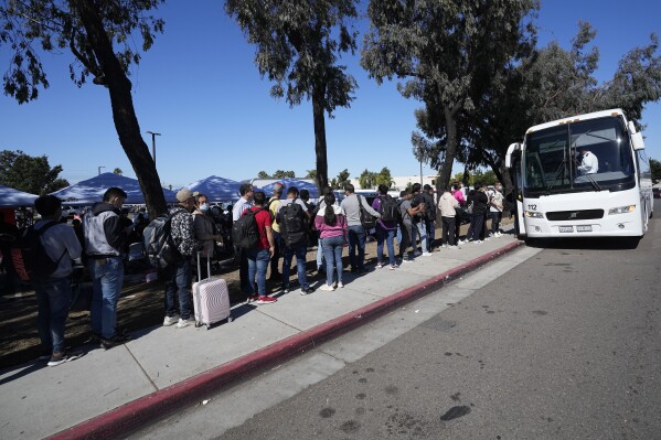 Migrants line up to take a bus to the airport Friday, Oct. 6, 2023, in San Diego. San Diego's well-oiled system of migrant shelters is being tested like never before as U.S. Customs and Border Protection releases migrants to the streets of California's second-largest city because shelters are full. (AP Photo/Gregory Bull)