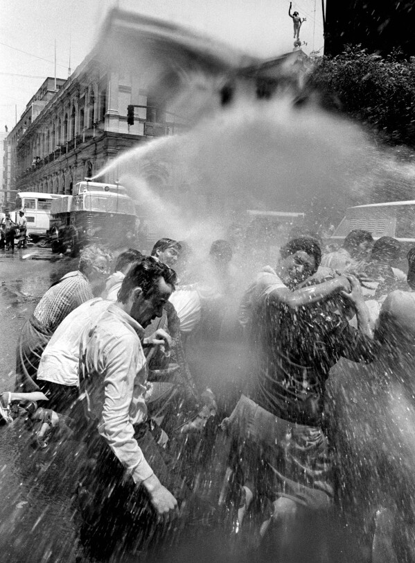 Water with tear gas mixed in is fired by police at protesters from the Movement Against the Torture of Sebastián Acevedo outside El Mercurio newspaper in downtown Santiago, Chile, Nov. 24, 1983. (AP Photo/Marco Ugarte)