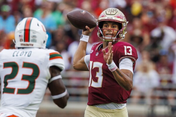 Florida State quarterback Jordan Travis (13) looks for a receiver as Miami linebacker K.J. Cloyd (23) closes during the first half of an NCAA college football game, Saturday, Nov. 11, 2023, in Tallahassee, Fla. (AP Photo/Colin Hackley)