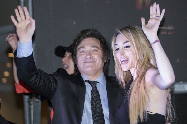 Presidential candidate of the Liberty Advances coalition Javier Milei, right, and his girlfriend Fatima Florez wave to supporters outside his campaign headquarters after winning the runoff election in Buenos Aires, Argentina, Sunday, Nov. 19, 2023. (AP Photo/Rodrigo Abd)