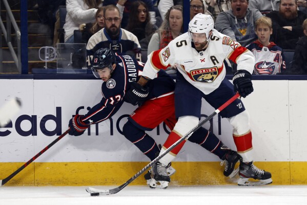 Florida Panthers defenseman Aaron Ekblad, right, reaches for the puck in front of Columbus Blue Jackets forward Johnny Gaudreau during the first period of an NHL hockey game in Columbus, Ohio, Sunday, Dec. 10, 2023. (AP Photo/Paul Vernon)