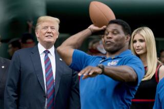 FILE - In this May 29, 2018, file photo, President Donald Trump, left, and his daughter Ivanka Trump, right, watch as former football player Herschel Walker, center, throws a football during White House Sports and Fitness Day on the South Lawn of the White House in Washington. On Tuesday, Aug. 17, 2021, Walker filed paperwork to enter the U.S. Senate race in Georgia after months of speculation, joining other Republicans seeking to unseat Democratic Sen. Raphael Warnock in 2022. (AP Photo/Andrew Harnik, File)