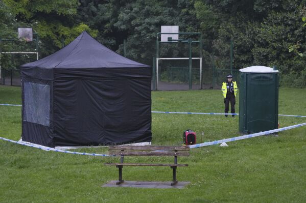 Police stand next to a black forensic tent in Grenfell Park, Tuesday May 21, 2024, in Maidenhead, England, west of London, where Matthew Trickett was found dead, Sunday, May 19. Trickett, one of three men charged earlier this month with assisting Hong Kong authorities with gathering intelligence in the United Kingdom, died in unexplained circumstances, British police said Tuesday. (Jonathan Brady/PA via AP)