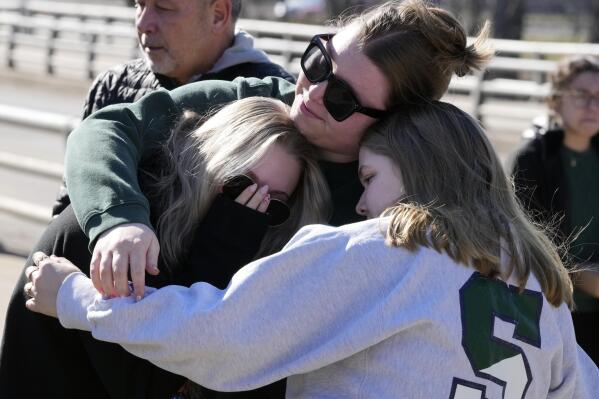 Michigan State University students embrace at The Rock on campus, Tuesday, Feb. 14, 2023, in East Lansing, Mich. Police say the gunman who killed himself hours after fatally shooting three students at Michigan State University was 43-year-old Anthony McRae. Police also say five people who are in critical condition Tuesday are also students. (AP Photo/Carlos Osorio)