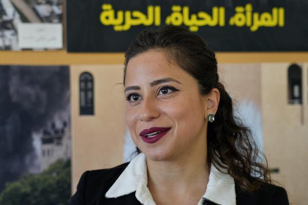 Deputy Regional Director for the Middle East & North Africa Aya Majzoub, speaks during an interview with The Associated Press in Beirut, Lebanon, Tuesday, March 28, 2023. Leading international rights group Amnesty International on Tuesday decried what it said were double standards by Western countries, which rallied behind a "robust response" to Russia's invasion of Ukraine but remain "lukewarm" on issues of human rights violations in the Middle East. The Arabic Words in the background read "Woman, life, freedom." (AP Photo/Bilal Hussein)
