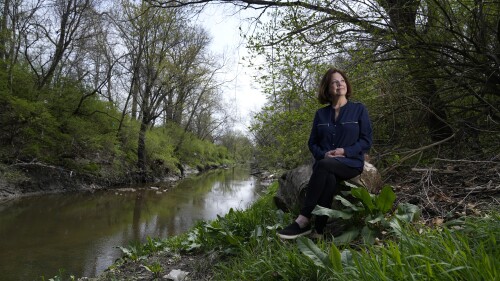 Susie Gaffney poses for a photo along Coldwater Creek near where she used to live Friday, April 7, 2023, in Florissant, Mo. The creek was contaminated when nuclear waste from the Manhattan Project flowed into the waterway past homes, schools and businesses. St. Louis played an important role in the country’s effort to build the first nuclear weapon. (AP Photo/Jeff Roberson)