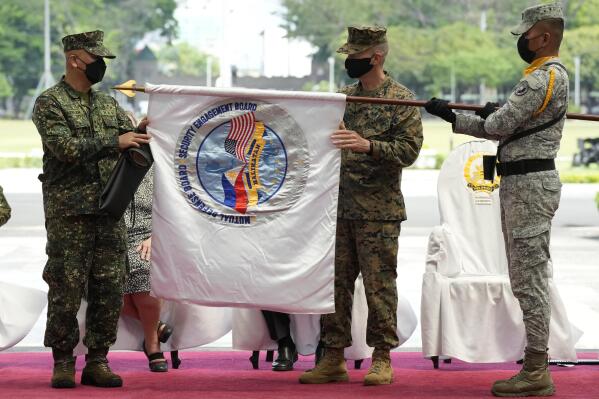 Philippines Exercise Director Major Gen. Charlton Sean Gaerlan of the Philippine Navy, left, and U.S. Exercise Director Major Gen. Jay Bargeron, center, of the U.S. Marine Corps unfurls the "Balikatan" or "Shoulder to Shoulder" flag during opening ceremonies of military exercises Camp Aguinaldo, Quezon City, Philippines on Monday, March 28, 2022. Thousands of American and Filipino forces opened on Monday one of their largest combat exercises in years that will include live-fire training, urban assaults, amphibious landing and coastal defense in the northern Philippine region near its sea border with Taiwan. (AP Photo/Aaron Favila)