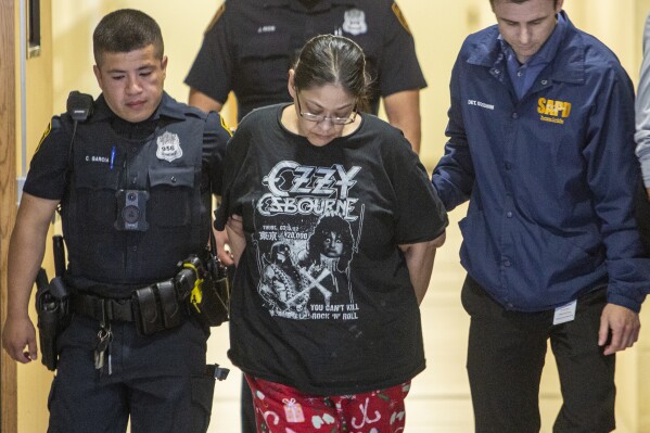 Myrta Romanos is escorted Wednesday, Jan. 10, 2024, in San Antonio by San Antonio Police officers to a police car after she was arrested on charges related to the slayings of Savanah Soto and Matthew Guerra. (William Luther/The San Antonio Express-News via AP)