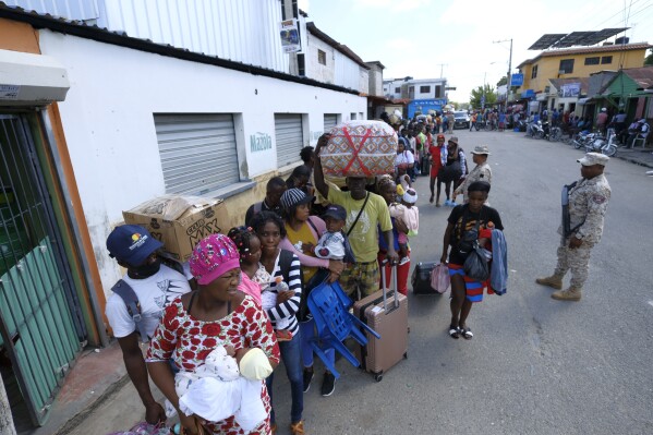 People wait on the closed border bridge to cross back into Haiti, from Dajabon, Dominican Republic, Wednesday, Oct. 11, 2023. The Dominican Republic partially reopened its border with Haiti on Wednesday to limited commercial activity nearly a month after shuttering the frontier in a continuing spat over construction of a canal targeting water from a shared river. (AP Photo/Ricardo Hernandez)