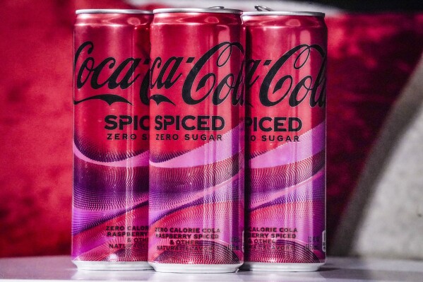 Cans of Coca-Cola Spiced, the beverage company's first new permanent offering to its North American portfolio in three years, are introduced at a livestream media event, Tuesday, Feb. 6, 2024, in New York. (AP Photo/Bebeto Matthews)