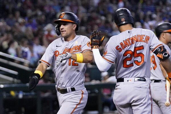 Baltimore Orioles' Adam Frazier, left, celebrates his run scored against the Arizona Diamondbacks with teammate Anthony Santander (25) during the second inning of a baseball game, Sunday, Sept. 3, 2023, in Phoenix. (AP Photo/Ross D. Franklin)