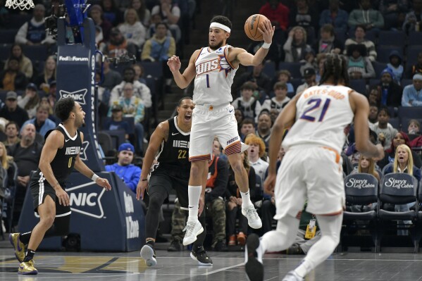 Phoenix Suns guard Devin Booker (1) grabs the ball ahead of Memphis Grizzlies guard Desmond Bane (22) in the first half of an NBA basketball game Friday, Nov. 24, 2023, in Memphis, Tenn. (AP Photo/Brandon Dill)