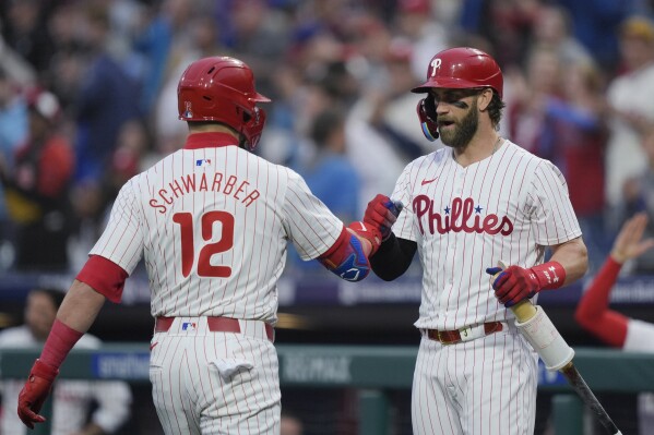 Philadelphia Phillies' Kyle Schwarber (12) celebrate his home run off Colorado Rockies pitcher Ryan Feltner with Bryce Harper during the first inning of a baseball game Wednesday, April 17, 2024, in Philadelphia. (AP Photo/Matt Rourke)
