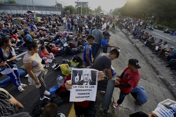A migrant holds a photo of Mexican President Andrés Manuel López Obrador that reads in Spanish: "The lives of migrants also matter" as their caravan stops to block the highway in Huixtla, Mexico, Wednesday, Nov. 8, 2023. About 3,000 migrants, mostly from Central America, are protesting for the government to issue them temporary documents allowing them to continue north to the U.S. border. (AP Photo/Edgar Clemente)