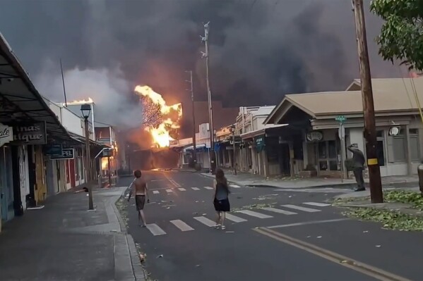 CORRECTS DATE TO AUG. 8 - People watch as smoke and flames fill the air from raging wildfires on Front Street in downtown Lahaina, Maui on Tuesday, Aug. 8, 2023. Maui officials say wildfire in the historic town has burned parts of one of the most popular tourist areas in Hawaii. County of Maui spokesperson Mahina Martin said in a phone interview early Wednesday says fire was widespread in Lahaina, including Front Street, an area of the town popular with tourists. (Alan Dickar via AP)