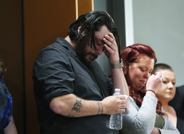 Devon Vestal, front, and his wife, Jess, react as they listen during a news conference to announce plans to sue the Littleton, Colo., school district for abuse suffered by their autistic child while riding the bus to class Tuesday, April 9, 2024, in Denver. (AP Photo/David Zalubowski)