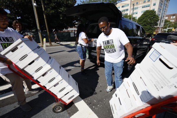 FILE - Activists haul boxes of signed petitions to Atlanta City Hall, Monday, Sept. 11, 2023, to force a referendum on the future of a planned police and firefighter training center. An analysis of petition entries by four news organizations finds it’s unclear whether petitioners have enough valid entries to force the citywide vote, with nearly half the entries unable to be matched to eligible registered Atlanta voters. (Miguel Martinez/Atlanta Journal-Constitution via AP, file) /Atlanta Journal-Constitution via AP)