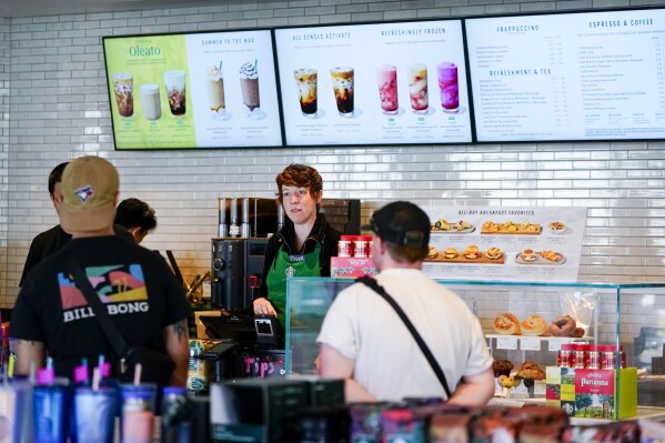 Starbucks employee Pyper takes customer orders at a Starbucks retail location, Wednesday, June 28, 2023, in Seattle. The company's goal to to cut waste, water use and carbon emissions in half by 2030. (AP Photo/Lindsey Wasson)