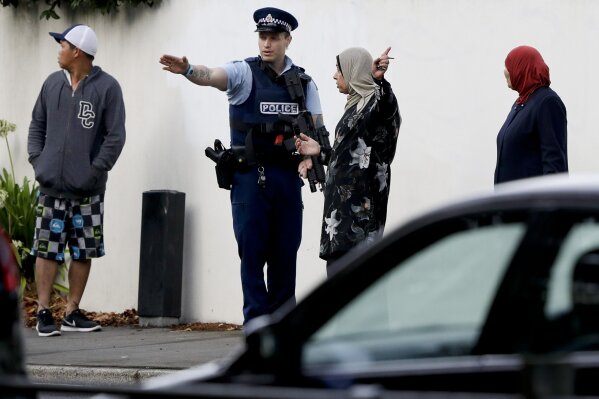 
              A police officer directs pedestrians neat the site of one of the mass shootings at two mosques in Christchurch, New Zealand, Saturday, March 16, 2019. (AP Photo/Mark Baker)
            
