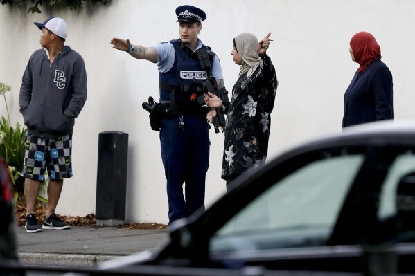 A police officer directs pedestrians neat the site of one of the mass shootings at two mosques in Christchurch, New Zealand, Saturday, March 16, 2019. (AP Photo/Mark Baker)