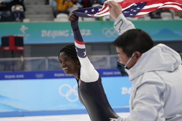 Erin Jackson of the United States skates on the ice hoisting an American flag with her coach Ryan Shimabukuro after winning the gold medal in the speedskating women's 500-meter race at the 2022 Winter Olympics, Sunday, Feb. 13, 2022, in Beijing.