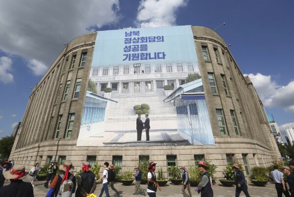 
              FILE - In this Sept. 12, 2018 file photo, people walk past under a banner showing North Korean leader Kim Jong Un, left, and South Korea President Moon Jae-in to wish for the successful inter-Korean summit at Seoul City Hall in Seoul, South Korea. South Korea’s liberal president faces growing skepticism at home about his engagement policy ahead of his third summit with North Korean leader Kim Jong Un. A survey showed nearly half of South Koreans think next week’s summit won’t find a breakthrough to resolve a troubled nuclear diplomacy. It comes as Moon’s approval rating is declining amid economic frustrations. The signs read: " We wish for the successful summit between North and South Korea." (AP Photo/Ahn Young-joon, File)
            