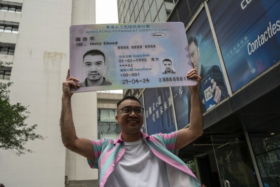 Activist Henry Tse, who won an appeal to change the gender on his ID card, poses with a mock ID card outside the immigration tower after receiving the new document in Hong Kong, Monday, April. 29, 2024. 2024. The Hong Kong transgender activist who fought a years-long legal battle to change the gender on his official identity card finally received the new document on Monday, vowing to continue working hard on the unfinished path of fighting for equality for his community. (AP Photo/Vernon Yuen)