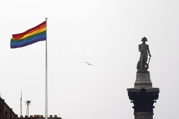 FILE -The rainbow flag, a symbol of lesbian, gay, bisexual, and transgender community, flies over a building next to Nelson's Column monument, right, in Trafalgar Square, central London, Britain, Friday, March 28, 2014. England's publicly funded health service says will not routinely offer puberty-blocking drugs to children at gender identity clinics. It says more evidence is needed about their potential benefits and harms. (AP Photo/Lefteris Pitarakis, File)