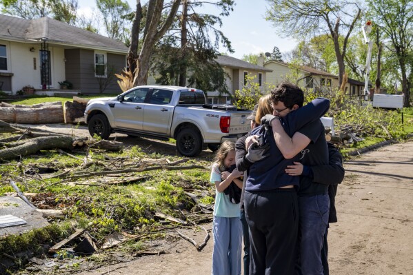 Neighbors embrace Penny Thomsen outside of her home in Pleasant Hill, Iowa, on Saturday, April 27, 2024. The Des Moines suburb was one of multiple cities hit as tornados ripped across the state Friday evening. (The Des Moines Register via AP)