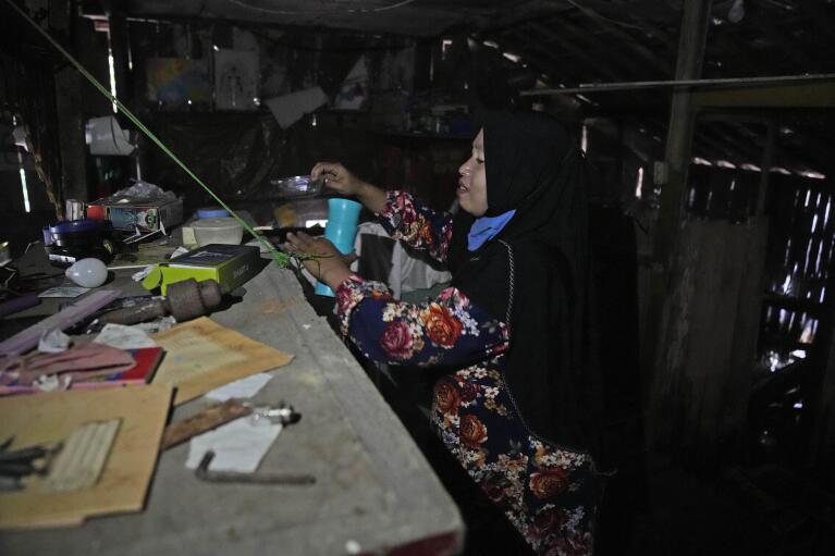 Asiyah, revisa los artículos dejados en la casa de su familia que abandonaron debido a las inundaciones en Modoliko, Java Central, Indonesia, el lunes 5 de septiembre de 2022. Ella y su familia finalmente se mudaron a tierras más secas, convirtiéndose en migrantes climáticos como lo habían hecho muchos de sus vecinos. Antes que ellos. (Foto AP/Dita Alangkara)