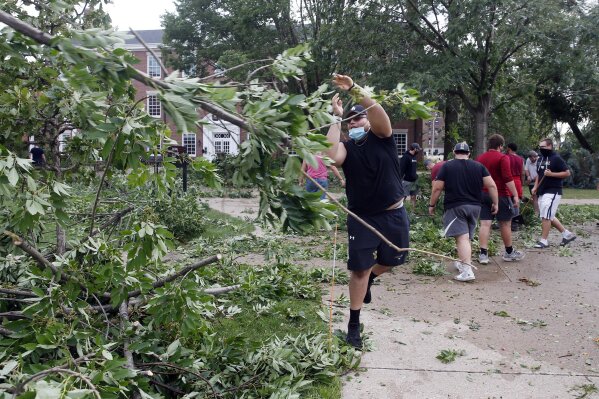 Coe College left tackle Joshua Robles clears trees with other members of the Coe College football team from campus sidewalks in Cedar Rapids after a powerful storm with straight-line winds moved through Iowa on Monday, Aug. 10, 2020. (Liz Martin/The Gazette via AP)