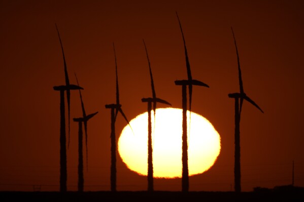 Wind turbines at the Buckeye Wind Energy are diffused by heat vapors as the are silhouetted against the rising sun, Sept. 30, 2024, near Hays, Kan. (AP Photo/Charlie Riedel, File)
