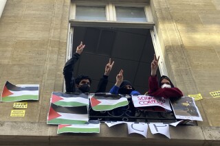 Estudiantes de la Universidad de Ciencias Políticas hacen el gesto de la victoria con la mano desde una ventana del centro, en París, el 26 de abril de 2024. (AP Foto/Jeffrey Schaeffer)