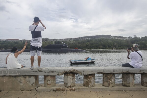 People watch the nuclear-powered submarine Kazan arrive at the port of Havana, Cuba, Wednesday, June 12, 2024. A fleet of Russian warships arrived in Cuban waters Wednesday ahead of planned military exercises in the Caribbean. (AP Photo/Ariel Ley)